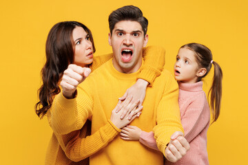 Young mad parents mom dad with child kid girl 7-8 years old wear pink knitted sweater casual clothes hold car like driving, hug pov safety belt isolated on plain yellow background. Family day concept.