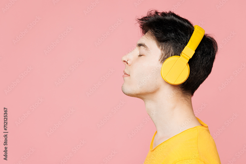 Poster close up side view young caucasian man he wears yellow t-shirt casual clothes listen to music in hea