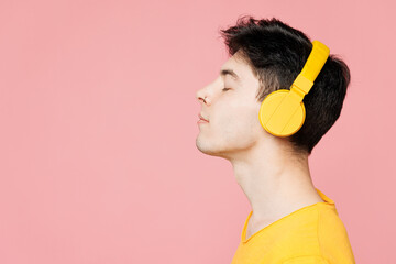 Close up side view young Caucasian man he wears yellow t-shirt casual clothes listen to music in...