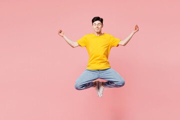 Full body young man wears yellow t-shirt casual clothes jump high hold spread hands in yoga om aum...