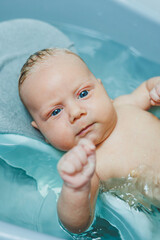 A newborn baby takes a bath. Parents bathe the child. The newborn is bathed. The newborn is smiling. Baby care