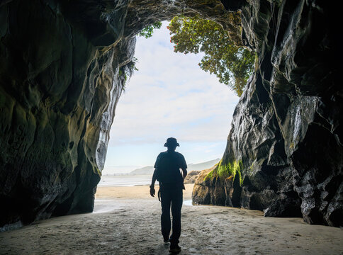 Man walking out of Muriwai cave. Muriwai Beach. Auckland.