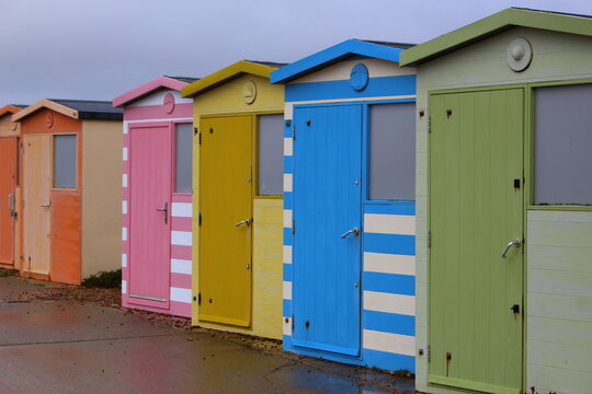 Colorful beach huts at the beach. Rainbow coloured beach huts along the walkway, closed on a rainy, overcast summer day in England. Beach closed concept, rain on my parade idea - Seaford Beach, Sussex