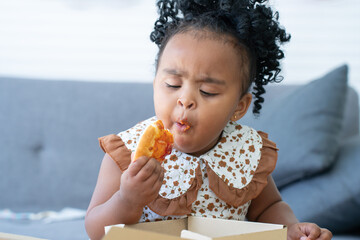 Portrait of Cute African child eating pizza at home. Kid enjoy and having fun with tasty lunch...