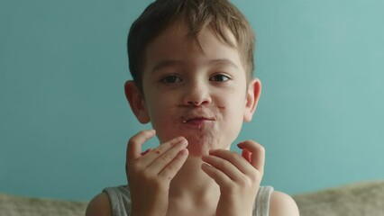 Portrait happy child 7 years old eats an appetizing sweet dessert donut in glaze. Cheerful caucasian little boy eats a sweet donut. Close-up of the mouth of a child eating sweet pastries. 4K.