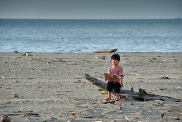 Cute Little Girls relaxing on the tropical beach and reading a book