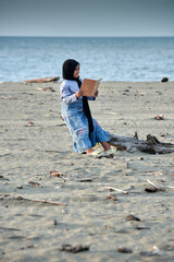 Little Girl reading a book on the tropical beach