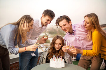 Young blond happy girl blows candles