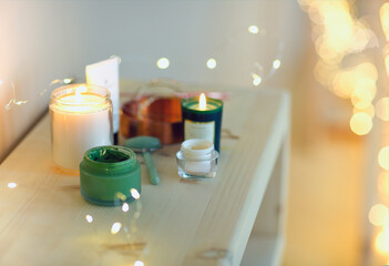 Burning candles and containers with various skincare cosmetics