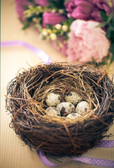 Flowers and easter nest with eggs on rustic wooden background