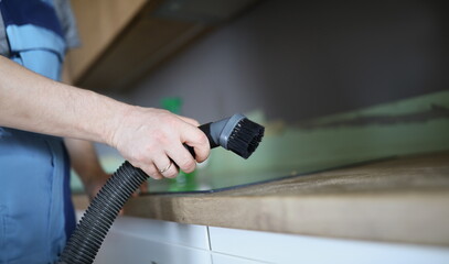 Close-up of male worker remove dust with vacuum cleaner, nozzle on cleaning device. Cleanup after renovation, remove mess from surface. Cleanup concept