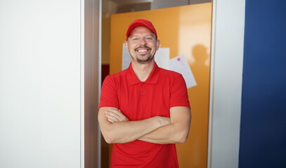 Portrait of happy man courier in red shirt and cap uniform, delivery worker. Best worker, positive...