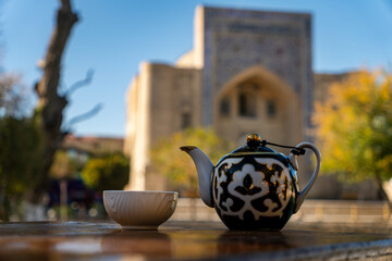 tea in oriental tradition. porcelain cup and teapot against the background of a beautiful madrasah, architecture in the medieval style of Central Asia.