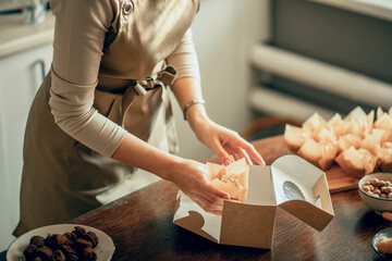 woman bakery shop owner holding delivery box for customer order. Bakery chef baking pastry and cake in the kitchen. Small business entrepreneur and food delivery concept.