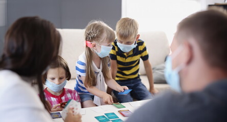 Portrait of kids in face masks, prevent virus spread in kindergarten, developing card game. Task...