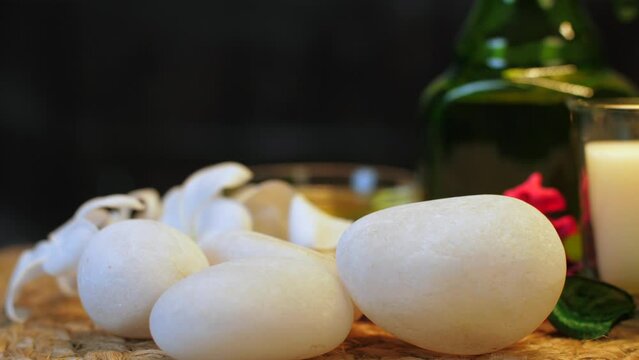 Stones for a rejuvenating spa session - flowers and burning candle. Aromatic chemical-free wellness program with a pebble massage for a lovely skin - pain reliever  aesthetic  body pain  relaxation...