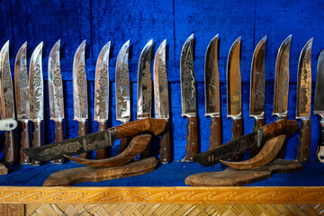 knives made of steel on counter on a blue background in the store. pchak is a traditional Uzbek...