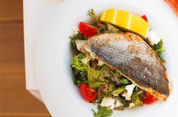 Warm salad with dorado fish on a plate