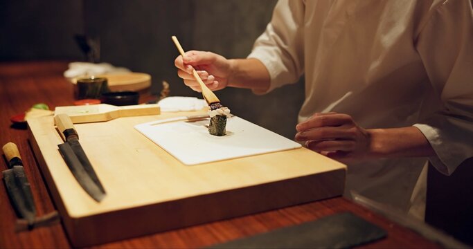Hands, food and sushi with cook in restaurant for traditional Japanese cuisine or dish closeup. Kitchen, table for seafood preparation and professional chef working with gourmet recipe ingredients