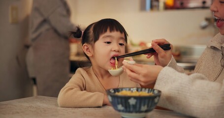 Family, Japanese and woman feeding daughter in kitchen of home for growth, health or nutrition....