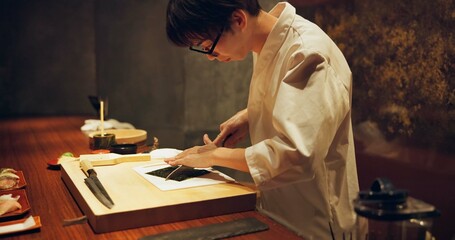 Japan chef, restaurant and cutting seaweed for sushi, glasses and precision with knife for raw fish...