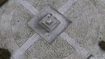 Bird's-eye winter view of a WWII cemetery, an obelisk among graves, highlighting the war's harsh reality under a cloudy sky.