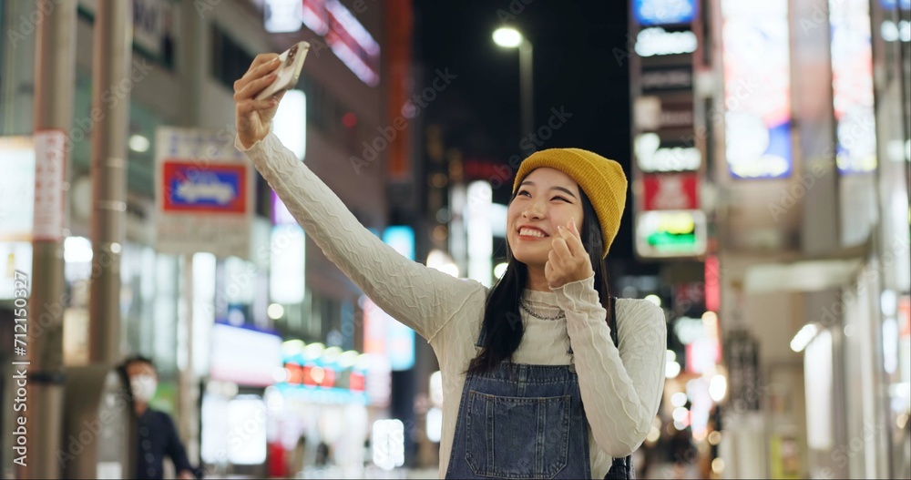 Poster Heart, hands and selfie by Japanese woman in a city for travel, adventure or journey outdoor. Love, emoji or happy lady influencer in Japan for content creation, blog or social media live streaming