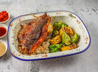 grilled sea bass or seabass fish with fried rice, grilled corn and broccoli served in isolated on grey background top view of singaporean food