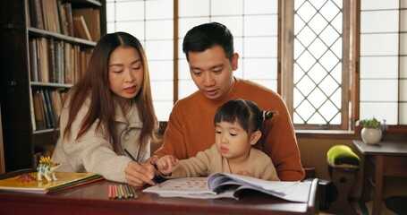 Mother, father and child teaching drawing at table in Japanese home for school, development or creative. Parents, daughter kid and pencil book project in Tokyo for study or education, art or bonding