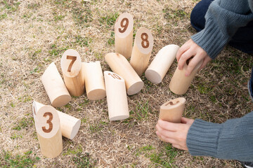 モルックの散らばったスキットルを並べる女性