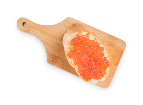 Red salty organic salmon caviar or fish roe on slice loaf of bread or canape with butter on wooden chopping board isolated on white background served for healthy breakfast full of protein and vitamins