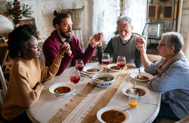 Family and religious concept. Group of multiethnic people with food praying before meal