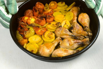 Top view of prepared food baked chicken with vegetables on baking tray. Woman in baking mittens turning baking sheet. Culinary, cuisine, recipe, cook, bake concept. Prepared cooked dinner, supper.