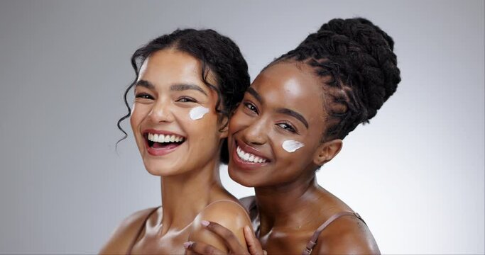 Women, cream and beauty with diversity in studio with facial treatment, happiness or glowing skin. Friends, model and portrait with smile for cosmetics, dermatology or body care on gray background