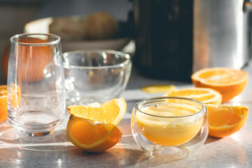 A glass of freshly squeezed orange juice and oranges on the kitchen table.