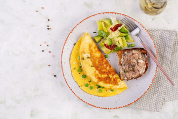 Omelette with green peas and toast with cod liver on white plate.  Frittata - italian omelet. Top view, flat lay