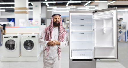 Saudi arab man leaning on a fridge in a store