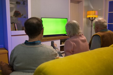 Family watching TV. Green screen. An adult man and his elderly parents are sitting at home on the...