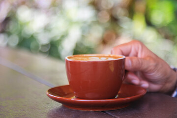 Woman holding a coffee cup on the table Woman holding hot latte coffee A coffee drink made from espresso and steamed milk.