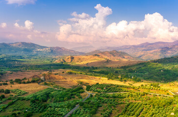 Naklejka premium scenic rustic landscape with green hills and farms in a mountain valley during colorful cloudy sunset