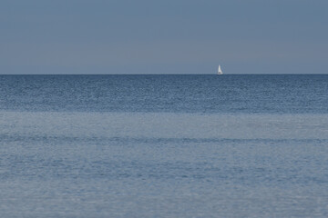 a sailing yacht sails on the horizon at sea