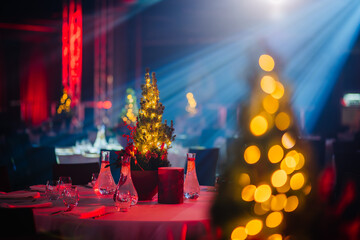 table with a lit Christmas tree centerpiece in a banquet hall, with a bokeh effect from the lights...