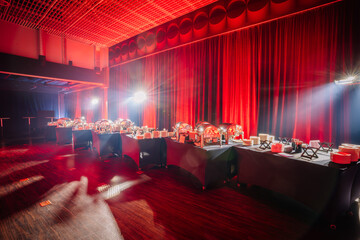 buffet setup in an event hall with serving dishes, under dramatic red drapery and intense stage...