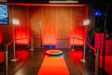 360 spinner photo booth setup in an event space with ambient red lighting, red carpet, lounge...