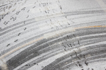 Fototapeta premium Footprints and tire marks on the snowy road