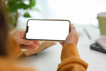 Woman in yellow sweater holding smartphone with empty screen. Closeup view