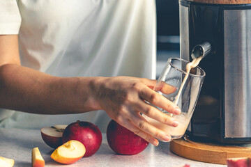 A woman makes apple juice at home with a juicer. - obrazy, fototapety, plakaty