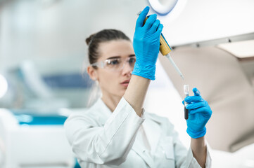 A female scientific researcher conducts a series of experiments in a modern bio laboratory with test tubes and a pipette. Laboratory assistant doing tests