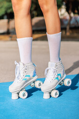 Fototapeta premium Anonymous woman in quad roller skates sneakers on colorful sports ground