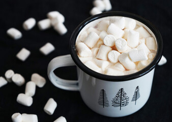 Cup of cocoa with marshmallows on a black background where white marshmallows are scatteredCup of cocoa with marshmallows on a black background where white marshmallows are scattered